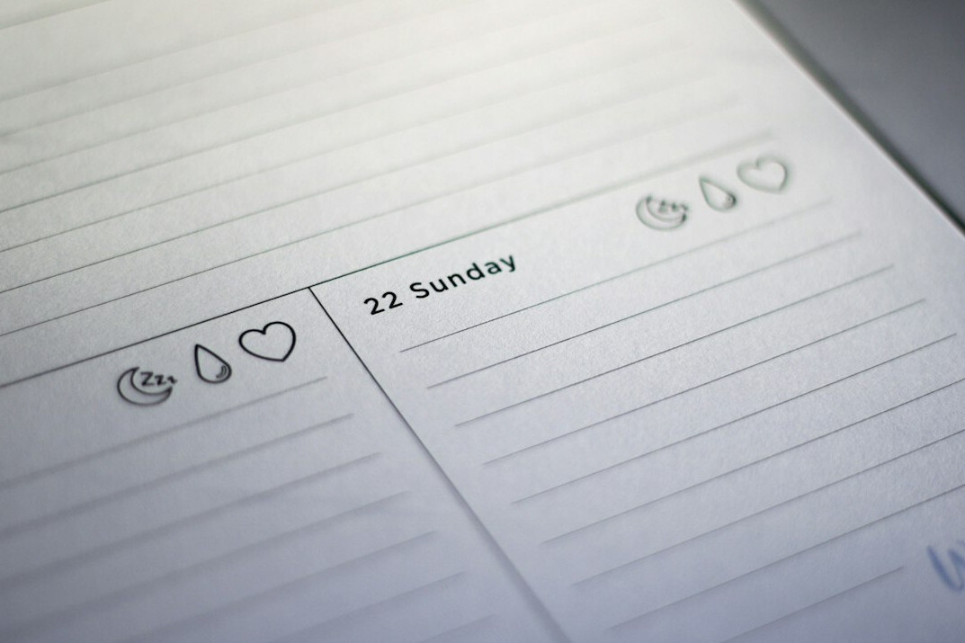 Hand writing a running order in a planner on a desk